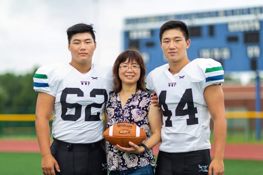 Brian and Andrew Zhong pose with their mom for their last year in the football program. 
