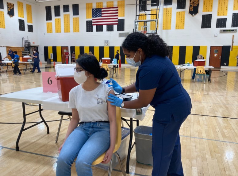 Above, Nandika Karnik (23), getting the vaccine in the gymnasium at GMS on May 24. 