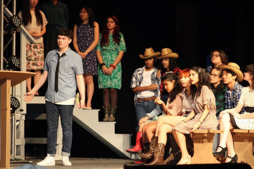 Connor Rossi (left) as Ren, surrounded by the ensemble as he delivers a monologue