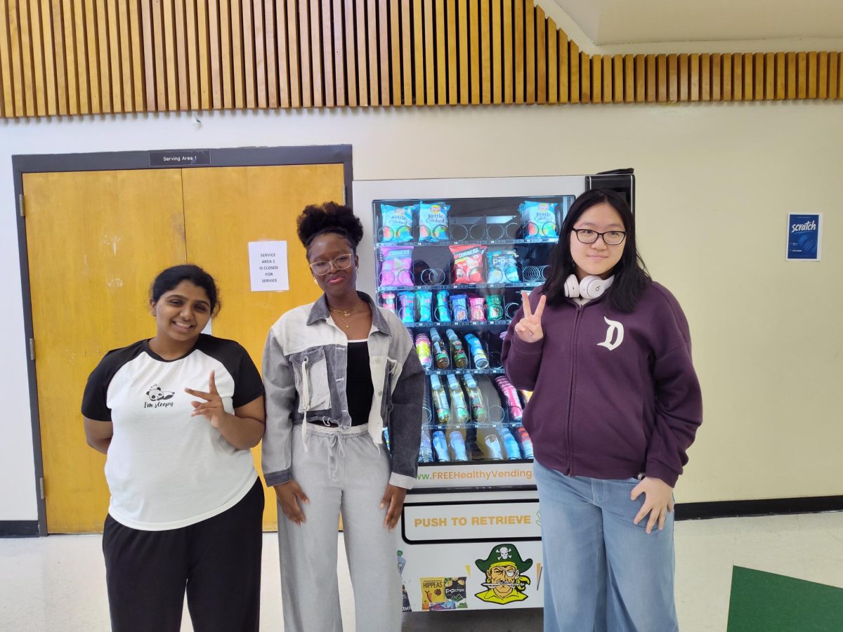 Haleema Hameed Aslam ('27), Bianka Blay Amihere ('26) and Samantha Liu ('28) posing in front of a vending machine.
