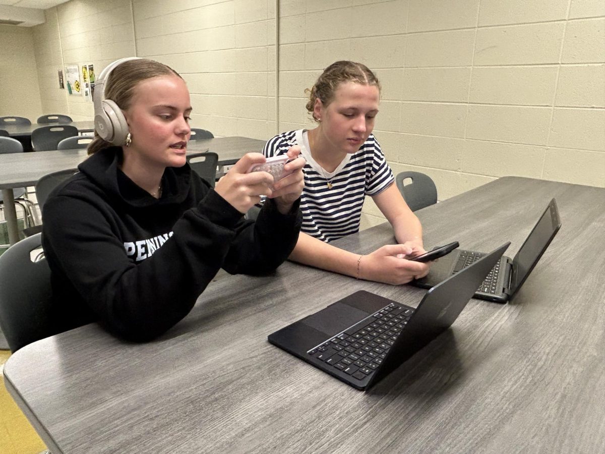 Eva Bernheisel ('29) and Emma Barrandon ('29) on their phones.
